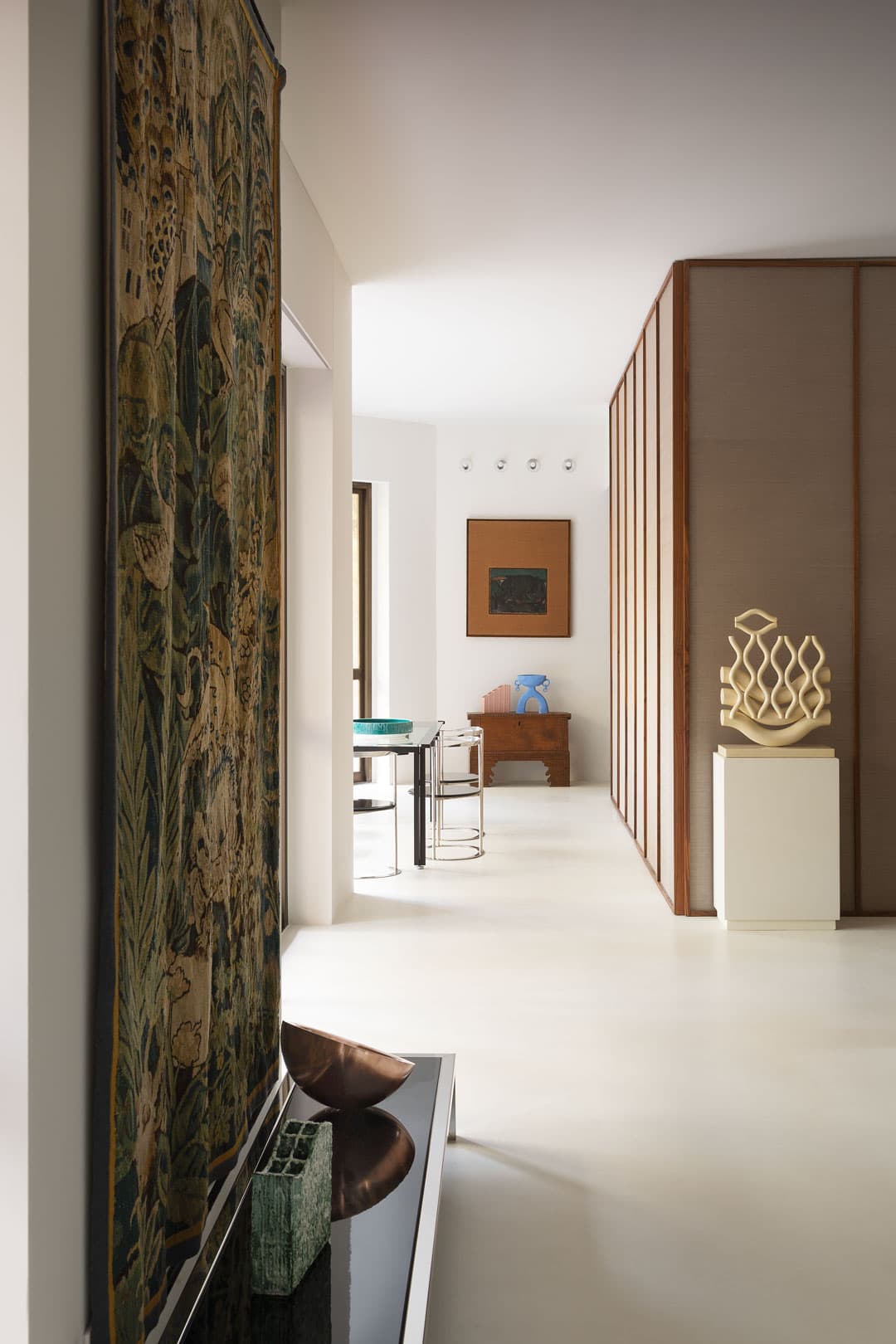 Modern interior, abstract sculpture, and wooden paneling. Natural light illuminates a table and artwork in the background.