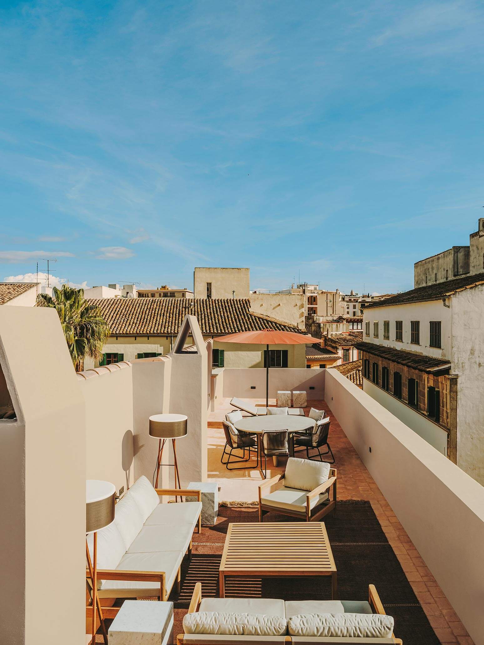 Rooftop terrace with seating area, tables, and chairs, surrounded by buildings.